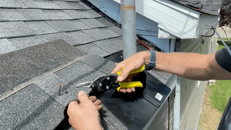 cutting shingle with tin snips to match the newly installed roof boot