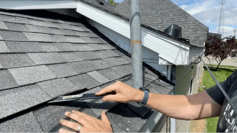 using a flat pry bar to loosen the shingles