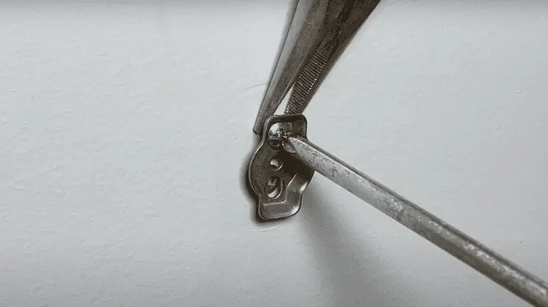 Use needlenose pliers and a screwdriver to back the screw out