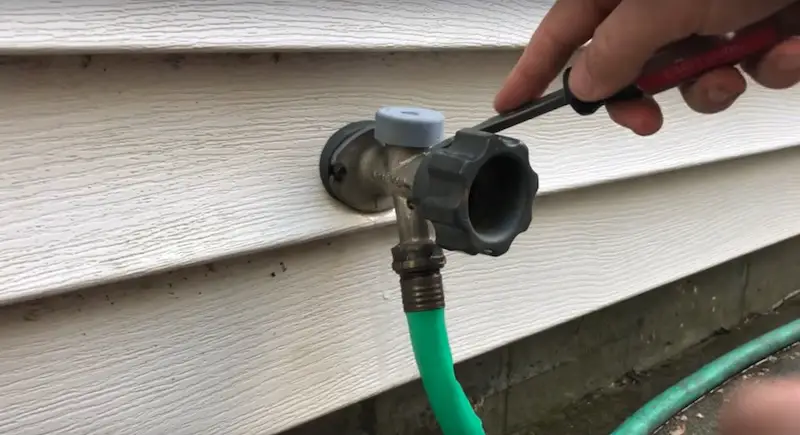 Removing the cap at the top of the faucet with flathead screwdriver