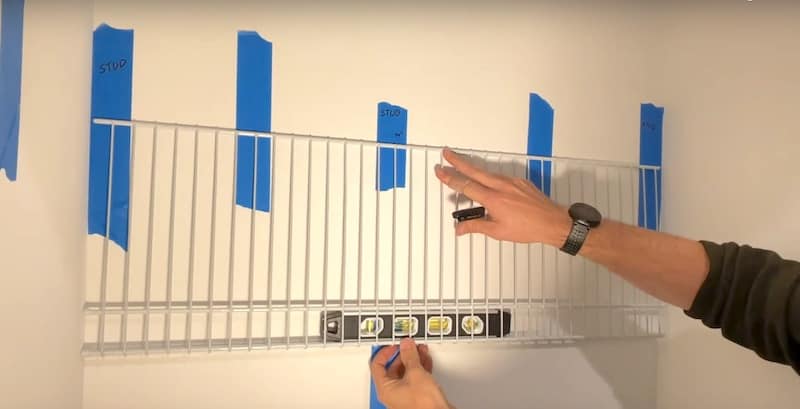Using the shelf and level as a guide for marking the mounting clip holes