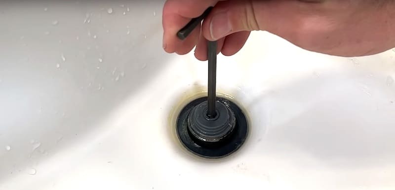 Removing the central section of the drain stopper with an Allen key