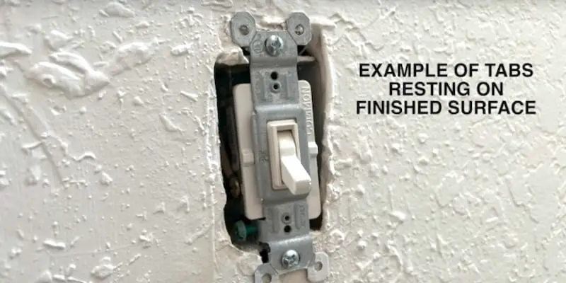 Example of outlet tabs resting on the outside surface of the wall