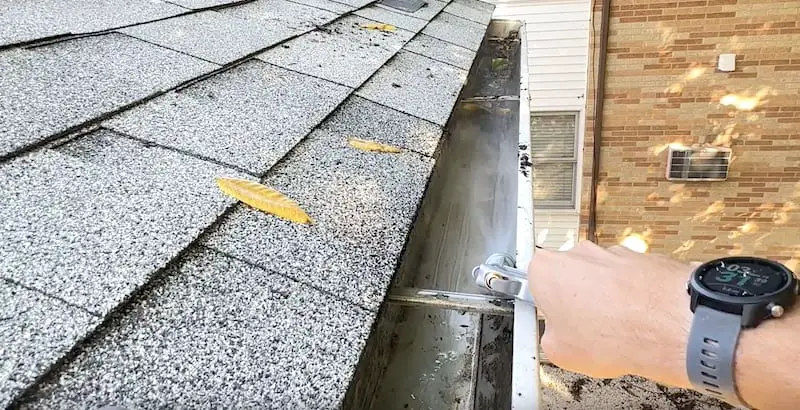 Flushing out the gutters with water to remove remaining dirt