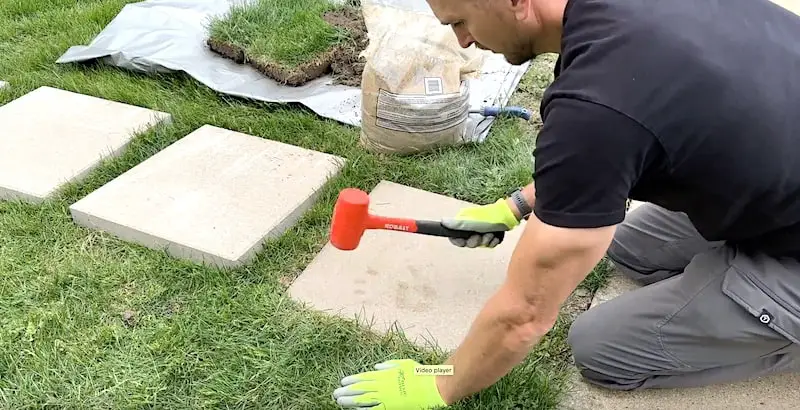Tamping the paving stone down with a mallet